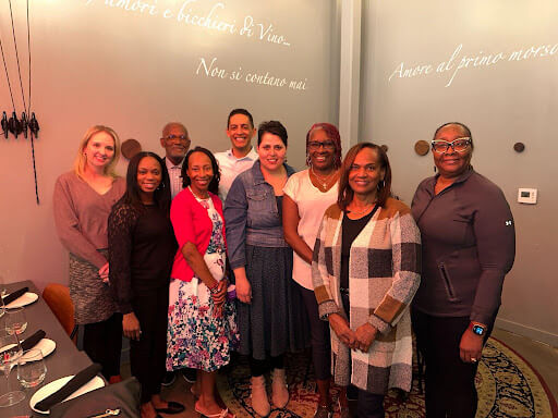 Dr. Gloria Thomas Anderson, founder of Heart Tones, smiling with a diverse group of team members and supporters.